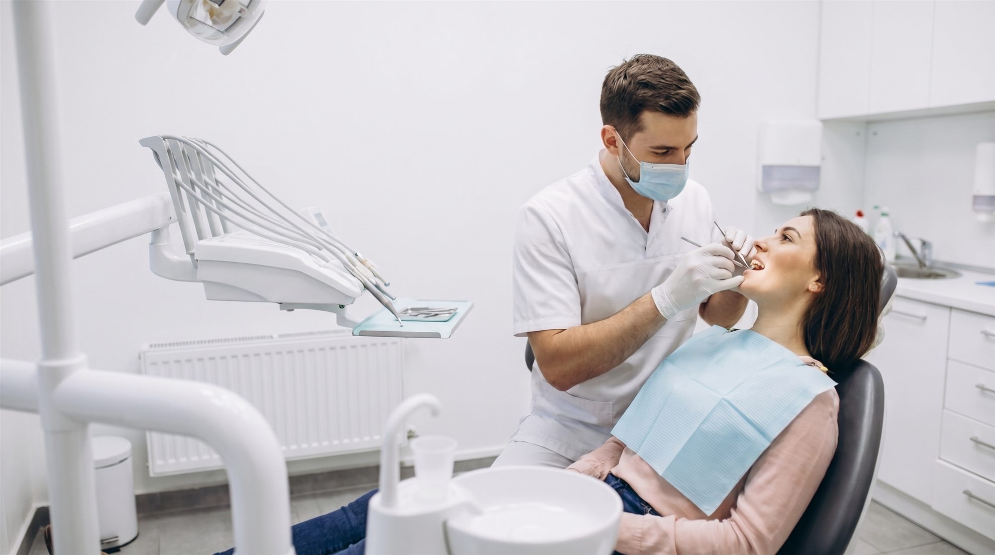 Zahnarzt behandelt eine lächelnde Patientin im modernen Behandlungszimmer